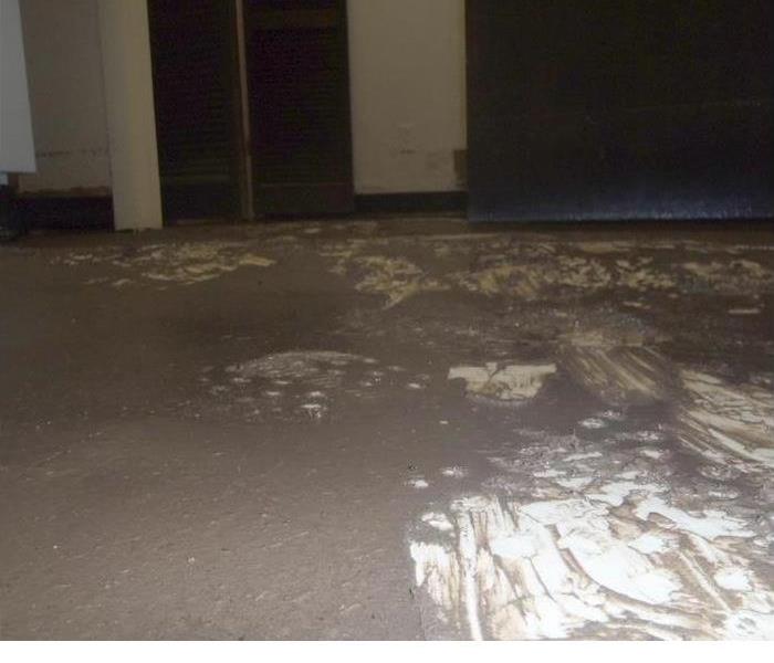 A room with water on the floor and water damaged walls 